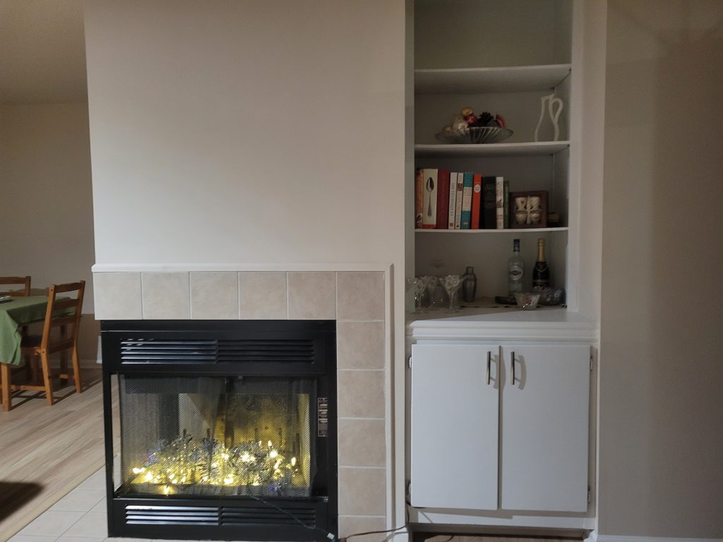 In-build shelves neatly organized near to fireplace.
